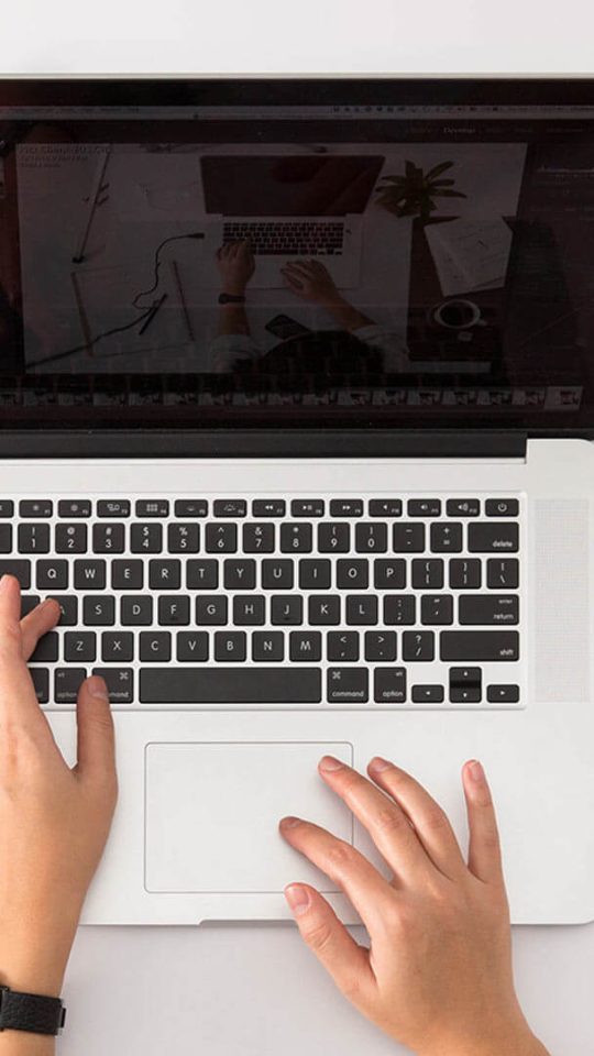 a person typing on a laptop computer with a plant and coffee cup at The  Jaxon