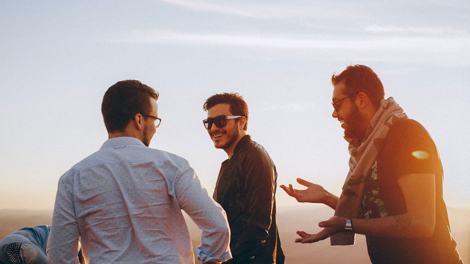 three men standing on top of a mountain with a sunset in the background at The  Jaxon