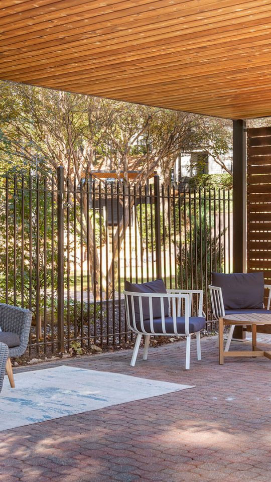 a wooden pergol with a bench and chairs at The Jaxon